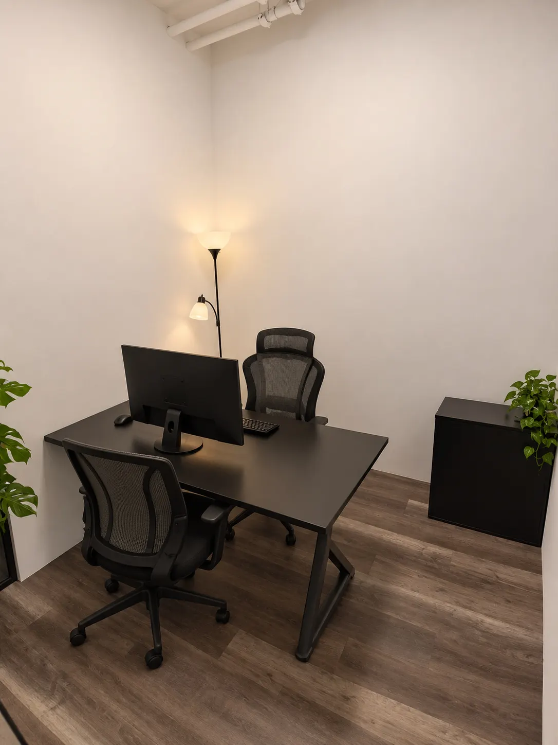 Bureau privé 104-3 au 2727 Coworking, Griffintown : bureau noir avec écran, fauteuil en filet et chaise visiteur, éclairé par un lampadaire