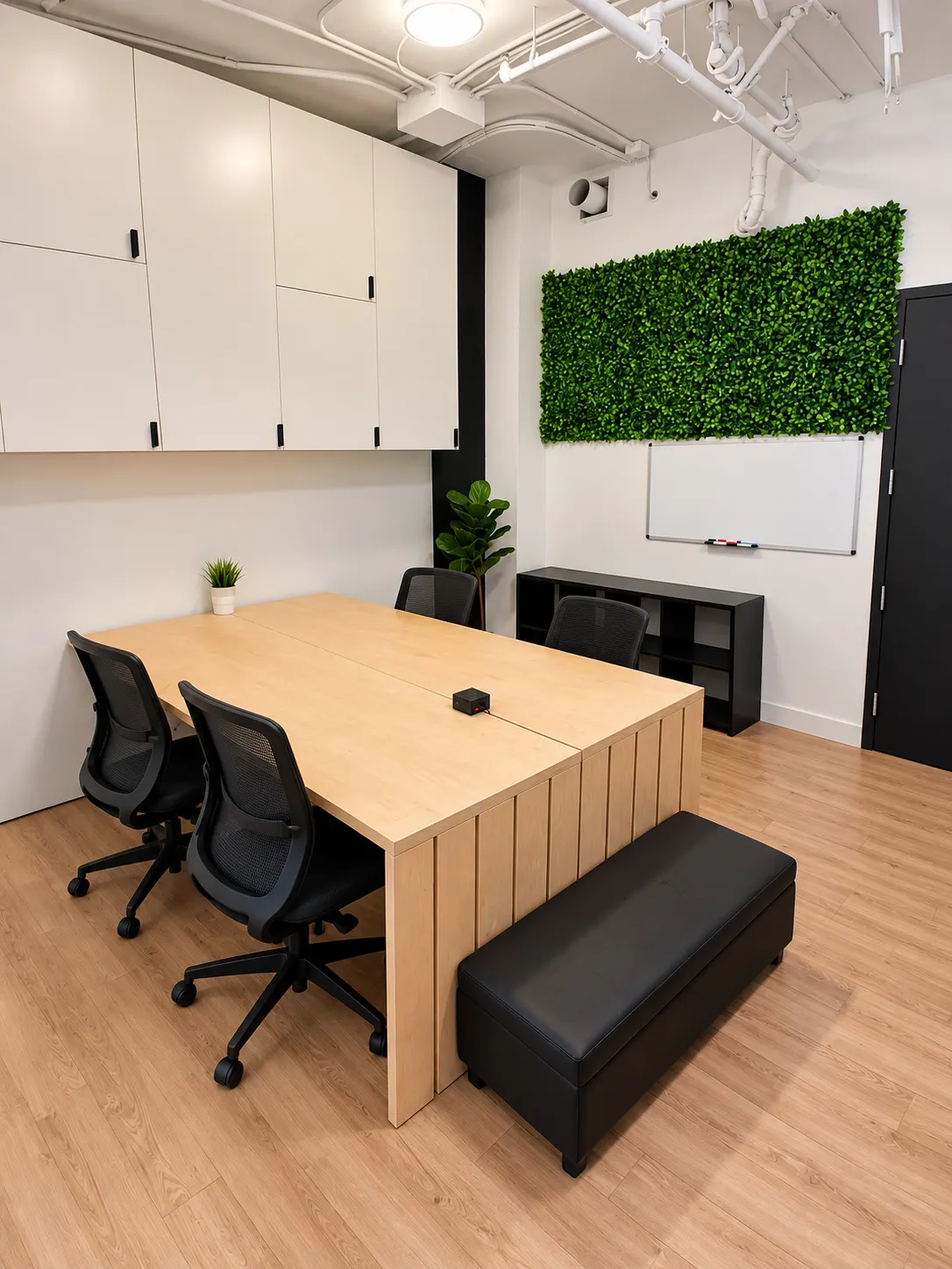 Bureau privé 106-1B au 2727 Coworking, Griffintown : table partagée en chêne pâle avec quatre fauteuils en filet, banc rembourré, mur végétal et tableau blanc