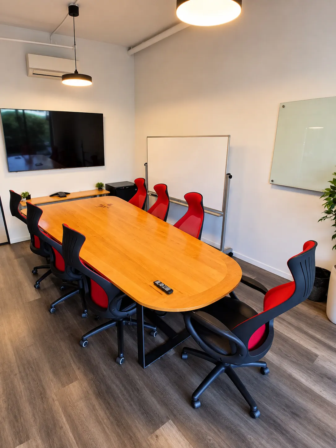 Salle de conférence du 2727 Coworking, Griffintown : longue table de bois pour dix, télé murale, tableau blanc sur roulettes et tableau de verre