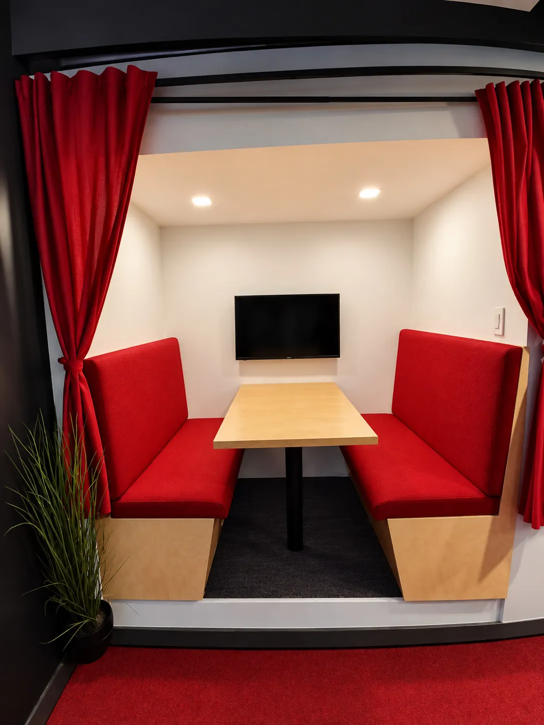 Meeting booth at 2727 Coworking, Griffintown: red banquettes facing a birch table, wall screen and red curtains
